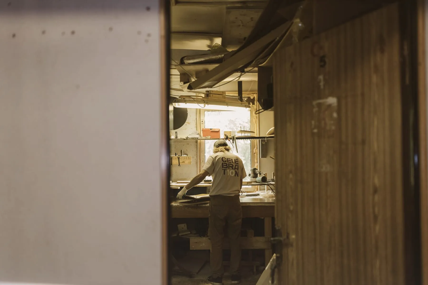Un artisan menuisier travaille à son établi, dans l'atelier Bernard