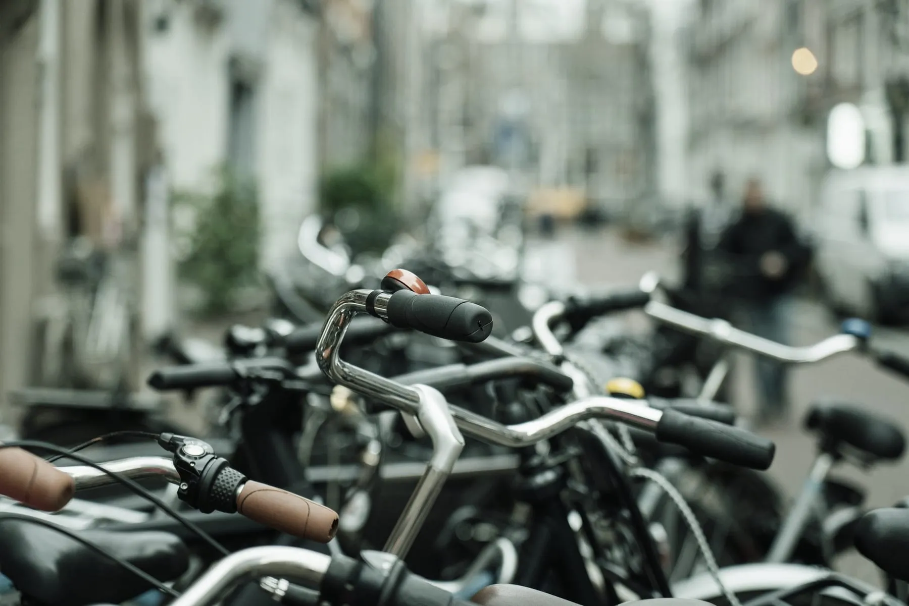 Guidon de vélo au premier plan d'une rue animée du centre-ville.