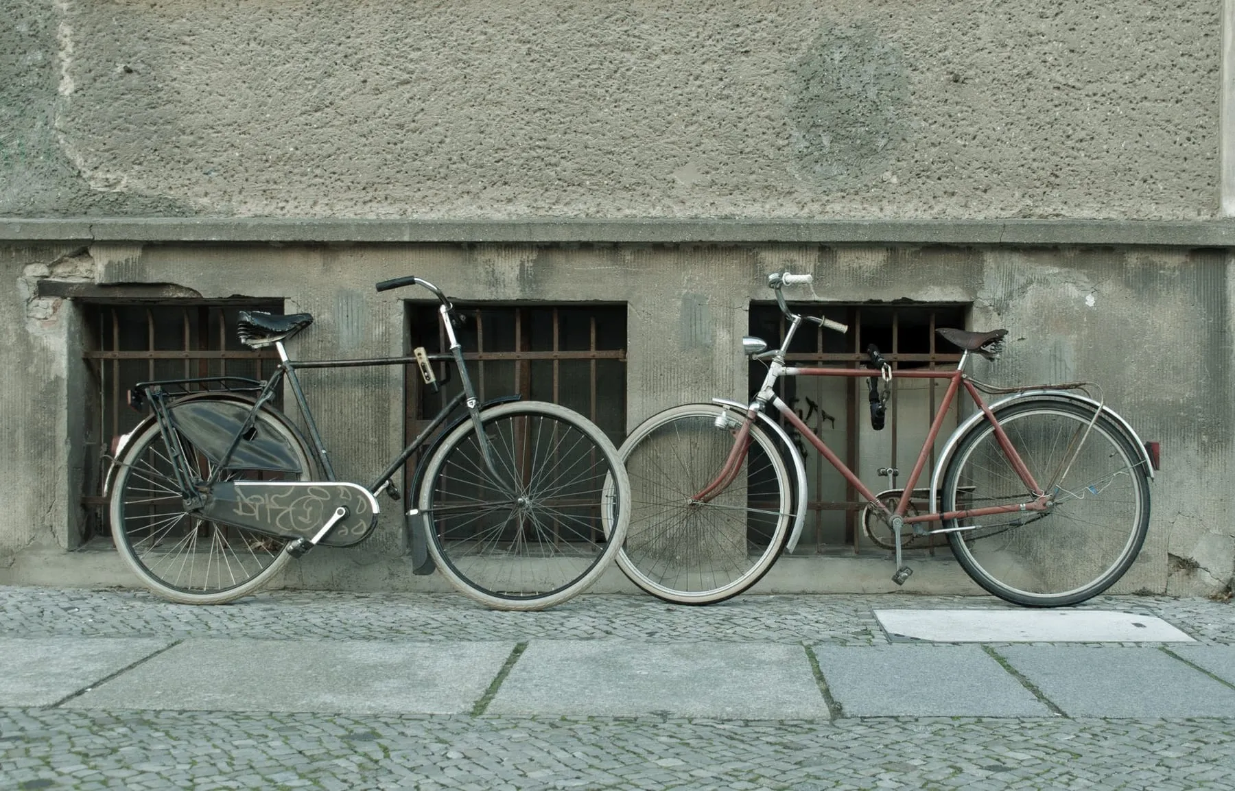 Deux vélos anciens appuyés contre un mur de rue pavée, à l'image de l'enseigne Pignon sur Rue.